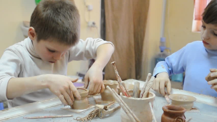 group of children decorating theitr pottery at clay school
