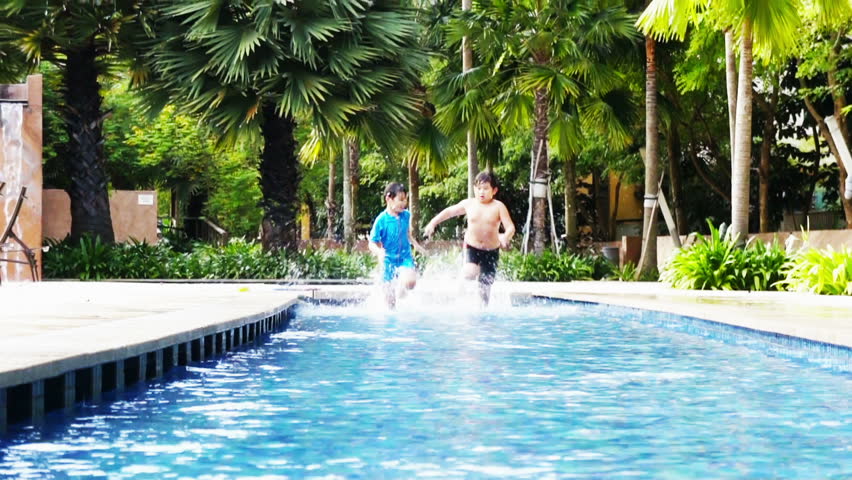 Two asian boys playing and racing in the pool.