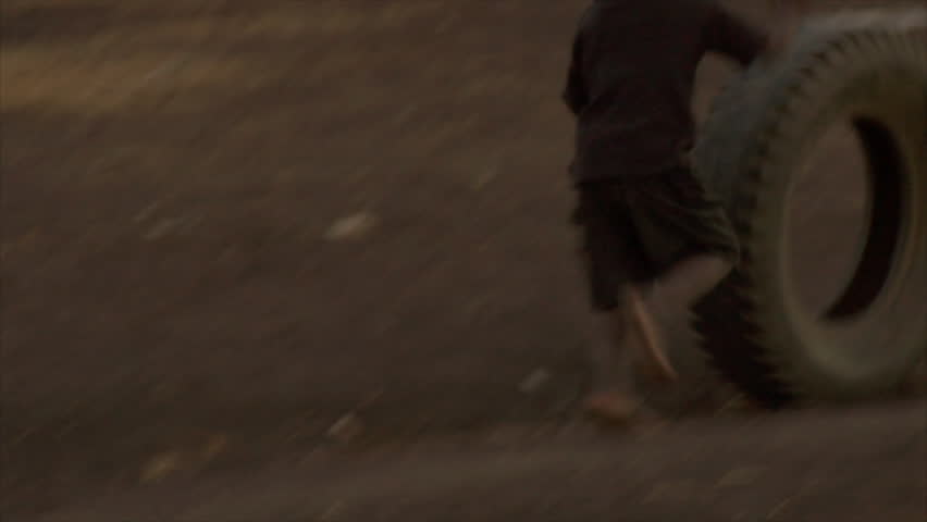 KENYA - CIRCA 2006: Two unidentified kids play with a car tire circa 2006 in Kenya.