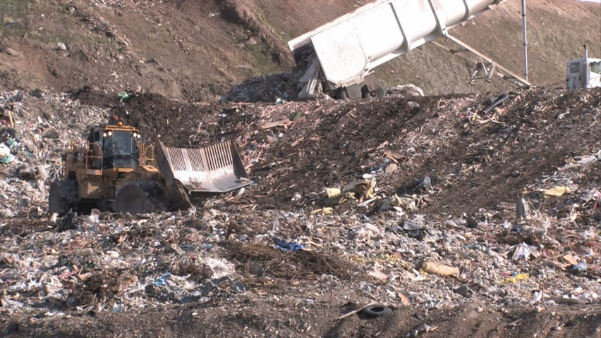 Garbage dump Utah. Bull dozers and large dump truck unloading and moving garbage and trash around. Pollution and debris from business residence household waste. Environmental waste non biodegradable.