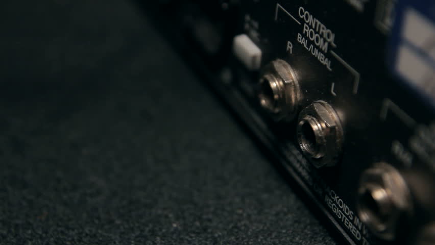 Inserting two XLR male cords into a audio mixer closeup.