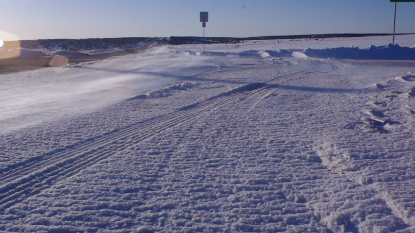 Snowing blowing acroos a frozen road