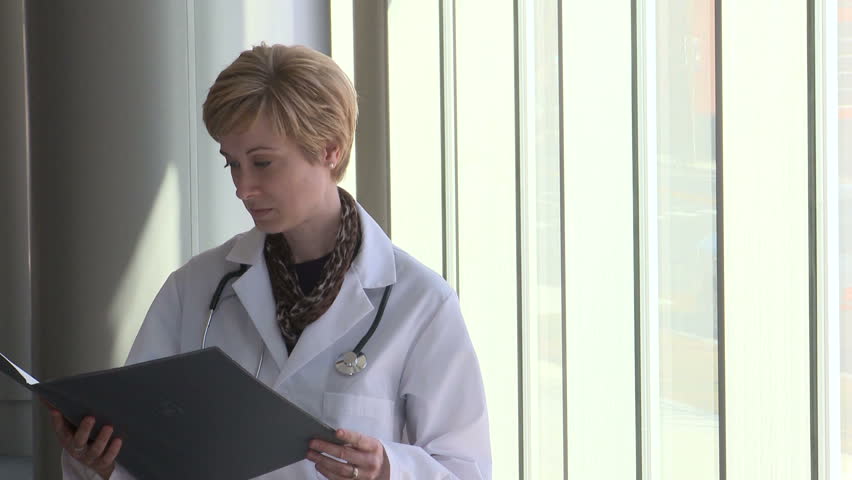Female doctor reading the patients chart as she enters