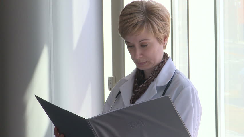 Female doctor reading patients char then looks up and smiles