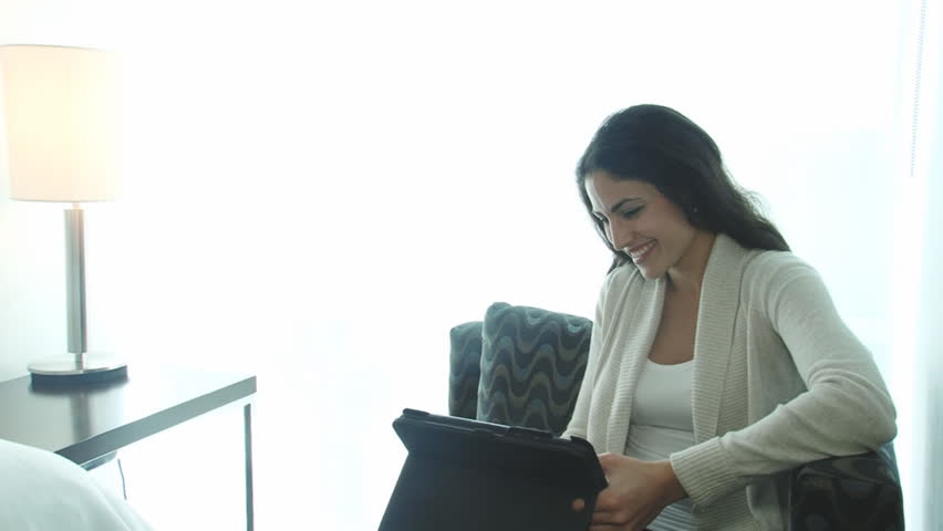 Happy traveling business woman working on tablet in hotel