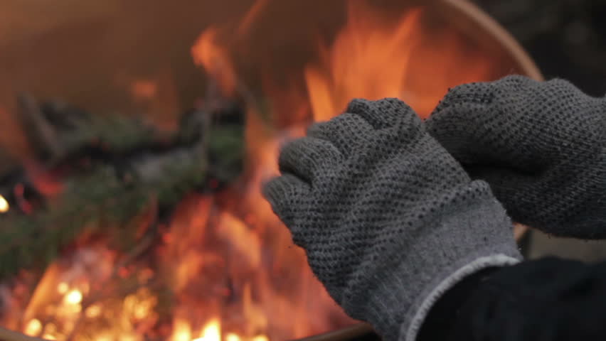 Homeless man warming his hands by a fire
