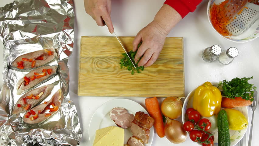 Female hands cooking ingredients for baked fish - chopping parsley