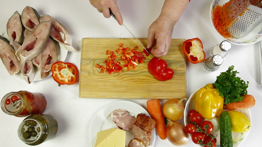 Female hands cooking ingredients for baked fish - chopping bell pepper. Shoot from above