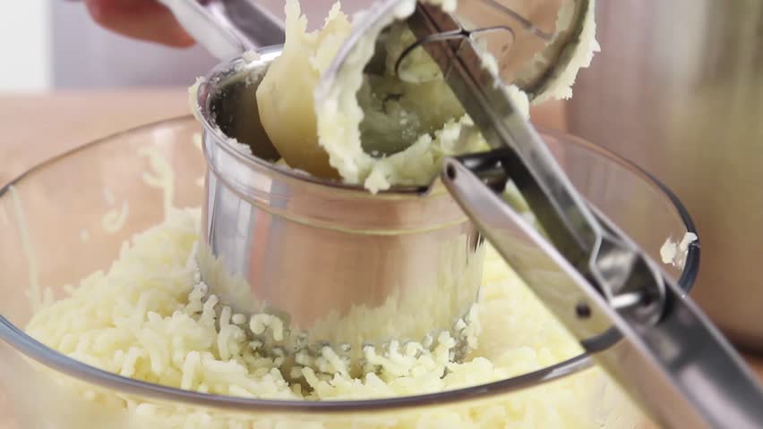 Cooked potatoes being passed through a potato ricer