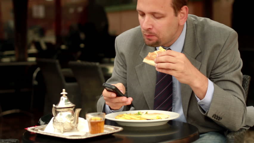 Businessman in cafe using cellphone, stabilized shot