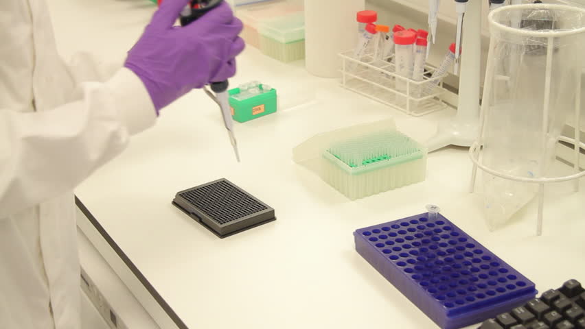 Scientist dropping liquid into vial in genetic laboratory