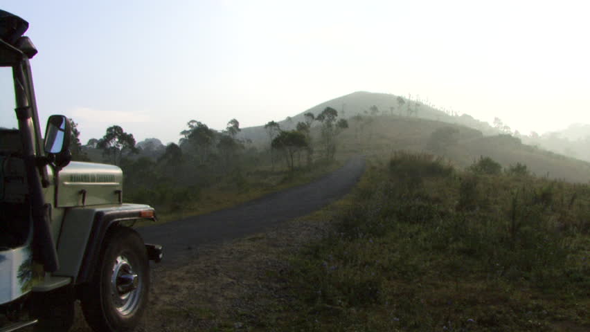 PAN, WIDE SHOT, SUV on hill overlooking Neyyar Wildlife sanctuary, Kerala, India