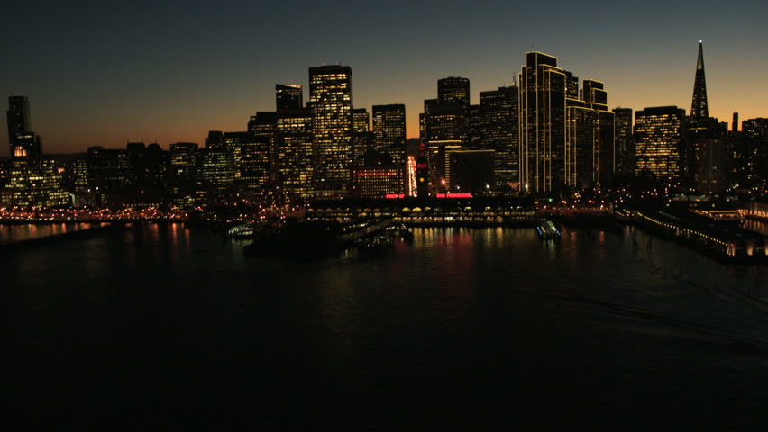 Aerial sunset low angle helicopter view of Fishermans Wharf city skyscrapers and the Oakland Bay bridge, San Francisco, USA
