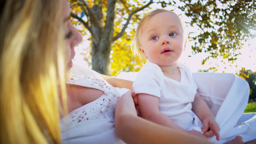 Blonde mother playing with her baby outside