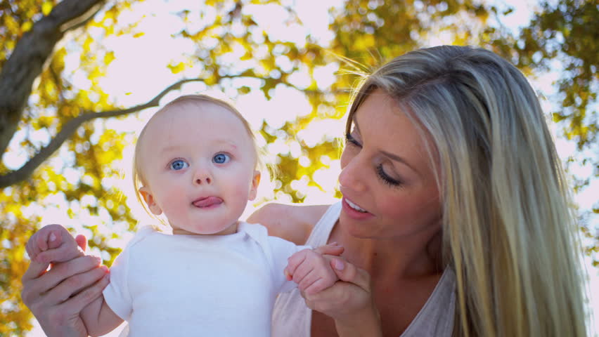 Cute baby being supported by his mother while the baby takes the first steps outdoors