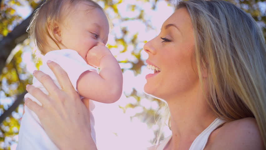 Beautiful young mother in close up outdoors tenderly holding her baby daughter