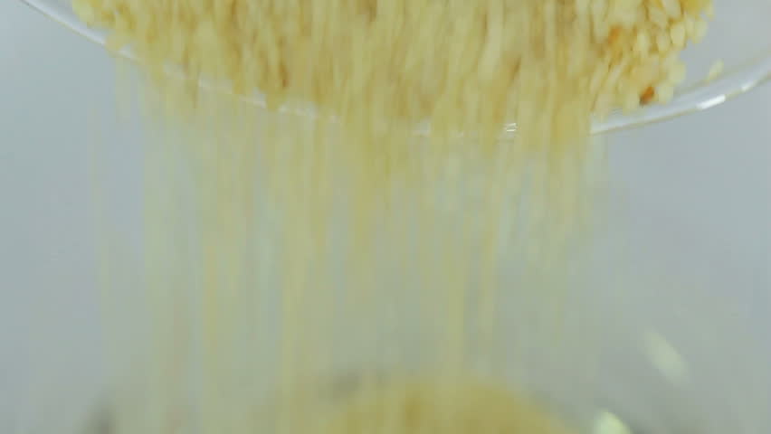 Pouring white sesame seeds into a glass.