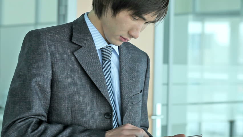 Close-up of a serious Asian businessman using a tablet