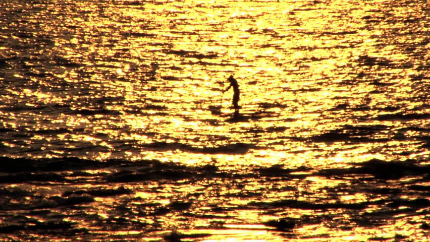 Man standing on a surfboard rowing