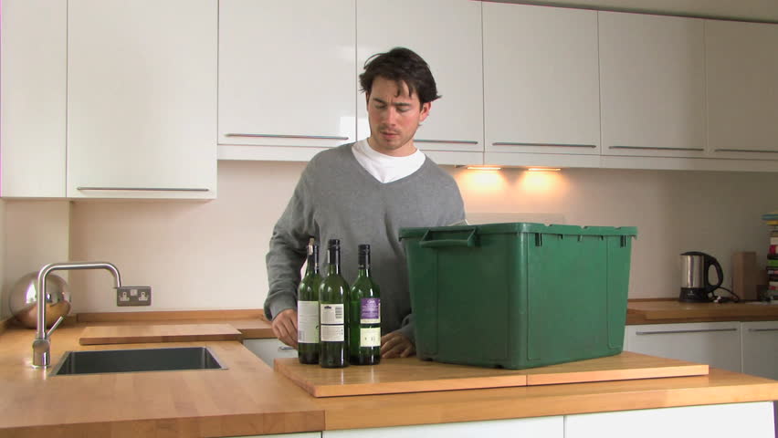 MEDIUM SHOT PAN OF A MAN RECYCLING BOTTLES