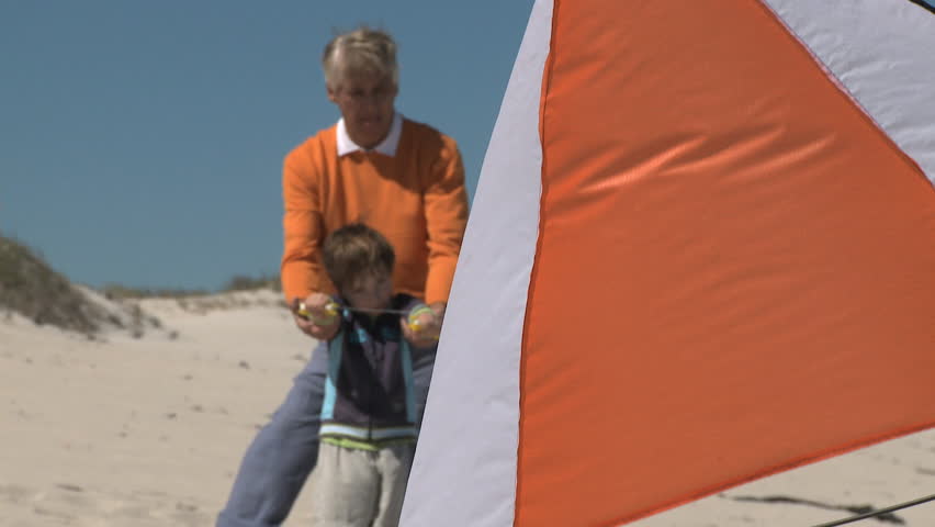 LONG SHOT OF A GRANDFATHER AND GRANDSON FLYING A KITE