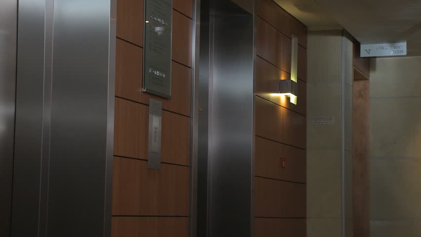 LONG SHOT PAN OF A BUSINESSWOMAN WALKING OUT OF A LIFT