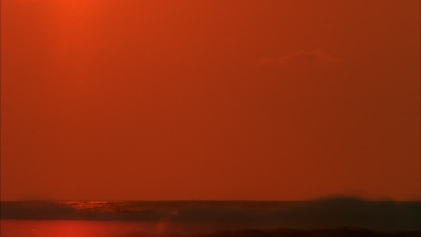 Sunset over Black Ocean Time-lapse - The sun slowly sets over the water as it pierces through smog and black sky.