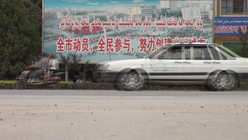 KASHGAR - 20 SEPTEMBER 2010: Traffic flows through the streets before a Communist slogan in Kashgar, China