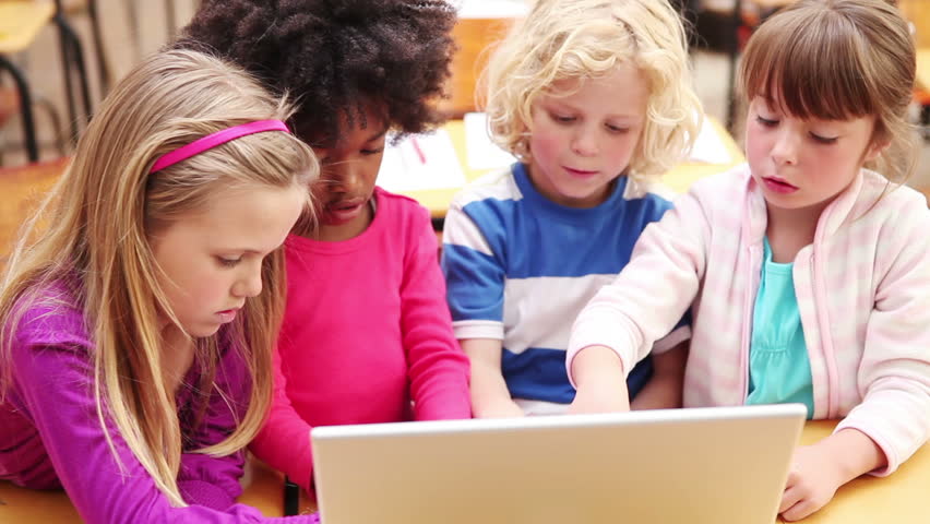 Smiling pupils using a laptop in the classroom