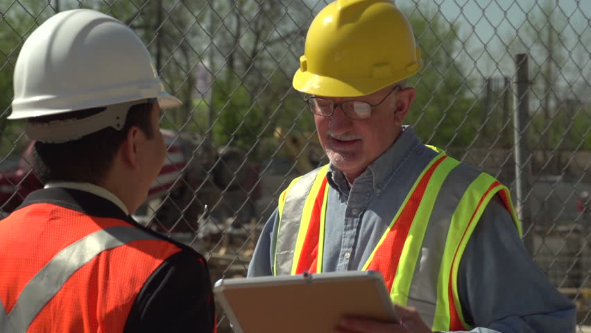 Construction worker and business man talking on site