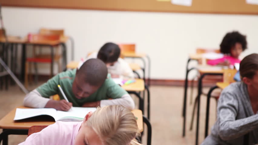 Serious pupils writing on their notebooks in the classroom - dolly shot 
