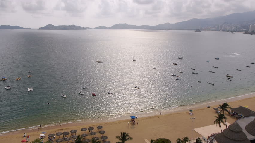 Acapulco Bay Afternoon (HD). High view of Acapulco Bay, waves and unrecognizable people at an Acapulco Mexico beach. All logos, signs and recognizable features and faces cloned or blurred out.