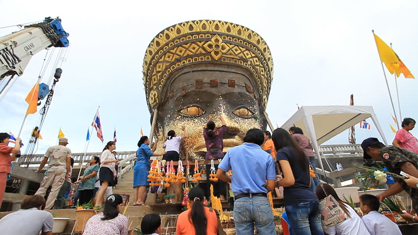 PHETCHABUN, THAILAND - JULY 15: People apply gold leafing to statue at Buddhist temple on July 15, 2011 in Phetchabun, Thailand.