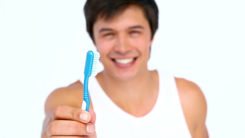 Man brushing and looking his teeth against white background