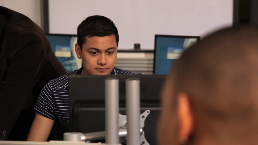 Male student asking teacher question in computer classroom