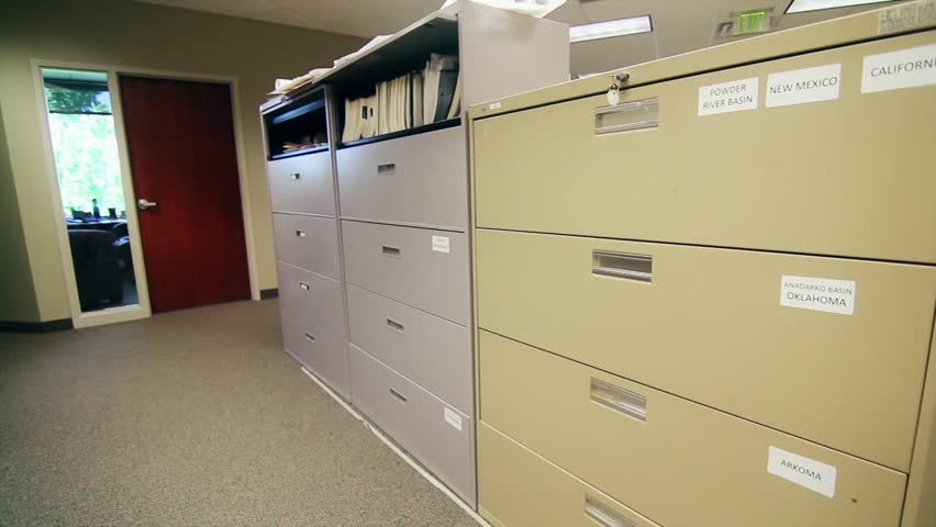 A man searches through large filing cabinets at his business