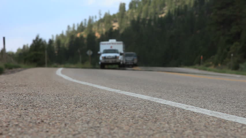 Pavement height shot of Cars coming down mountain road