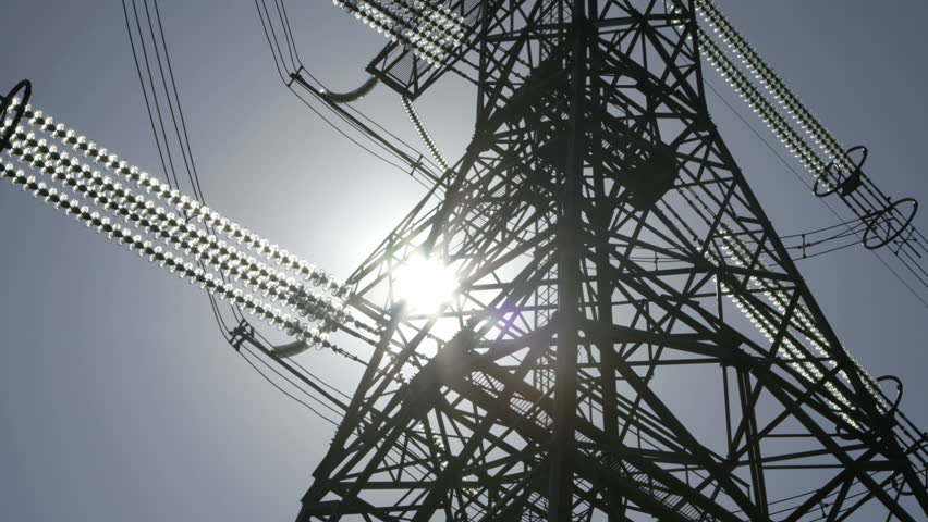 high voltage power pylons close up on against the sun