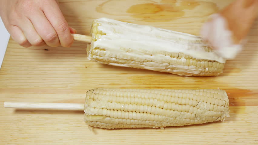 Preparing Mexican Corn  (HD). Preparing traditional Mexican corn or "Elotes" using spikes for handling, mayonnaise, grated cheese and spicy chile. These are common fast food in Mexico streets.
