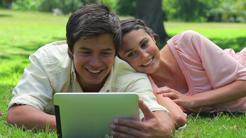 Smiling couple watching a tablet computer in the countryside