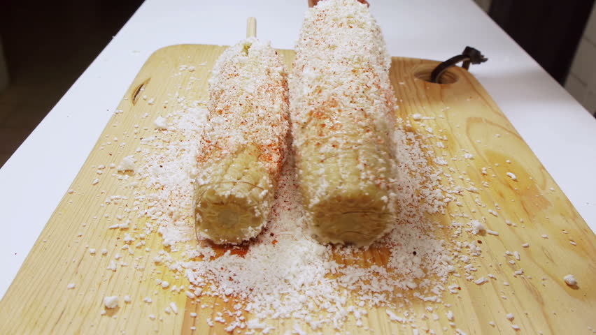 Preparing Mexican Corn Part Two (HD). Second part of a sequence of preparing traditional Mexican corn or "Elotes" using spikes for handling, mayonnaise, grated cheese and spicy chile.