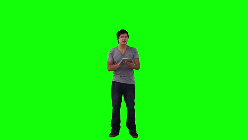 A man is using a tablet computer against a green background