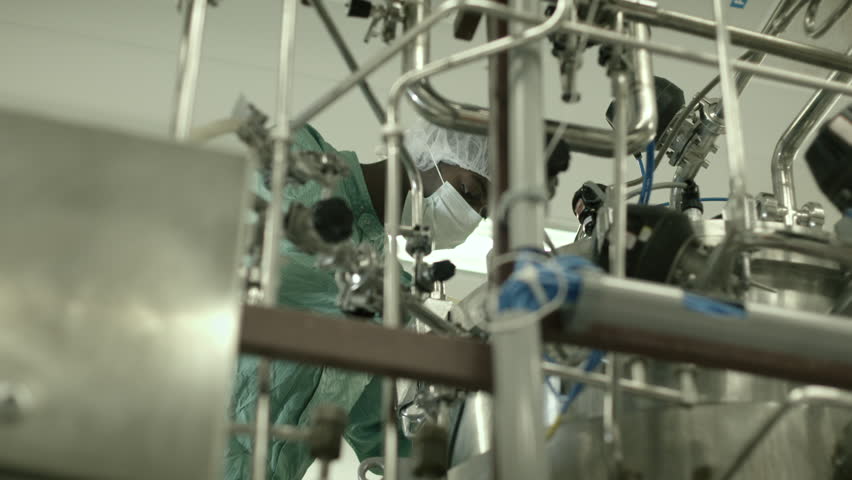 Man employed as lab technician and researcher at work in biotech industry with precision equipment