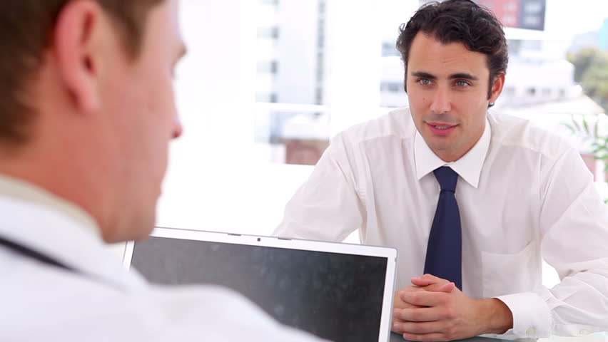 Serious businessman talking to a doctor in a bright office