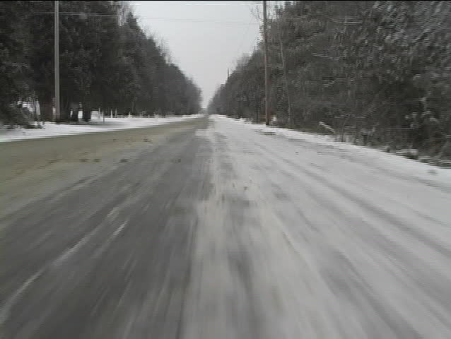 Rear view of snow covered road passing by during a drive in a remote area.