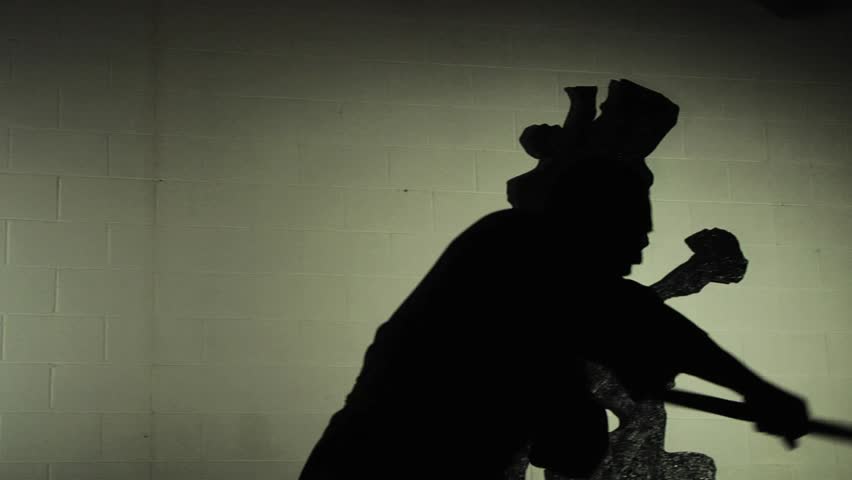 A Shaolin monk demonstrates in silhouette an ancient form of kung fu using a staff. Shot in slow motion. 