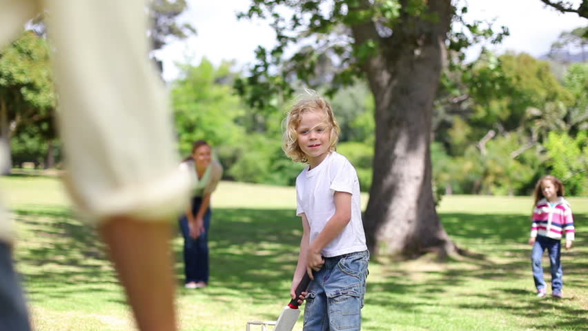 Boy playing baseball with his family in a park