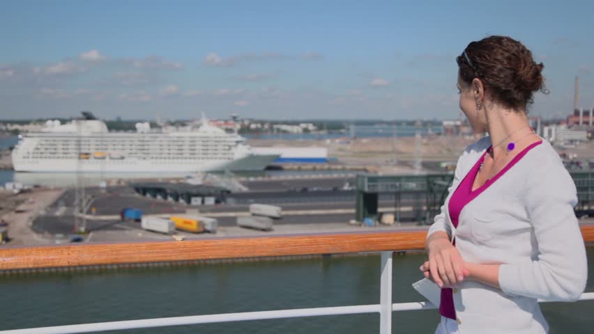 Woman puts piece of bread on handrail and gull takes it, at summer day in port
