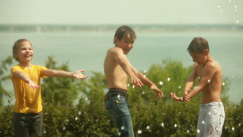 Children enjoying freshness of sprinkled water on a hot summer day