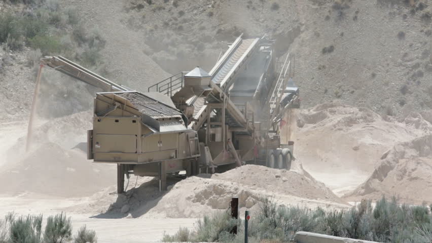 Mining of gypsum mineral. Dusty and dirt mountain side. Rock crusher processes stone into smaller chunks and powder.
